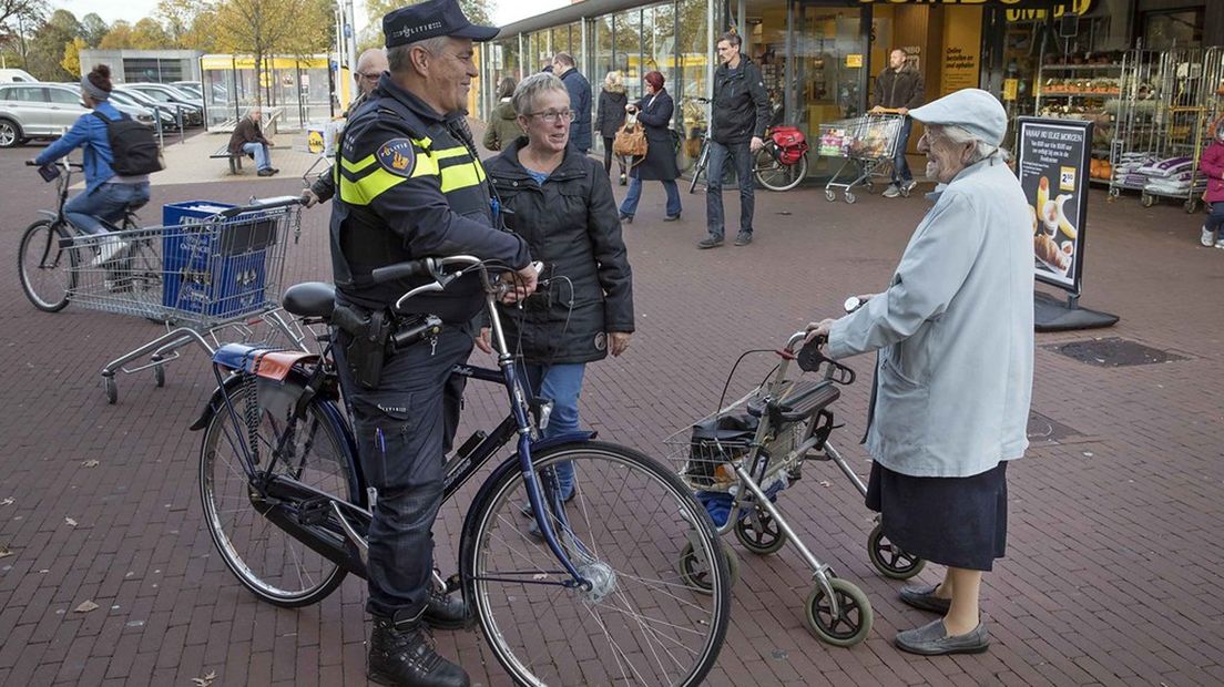 Een politieagent in gesprek met bewoners van Ter Apel.