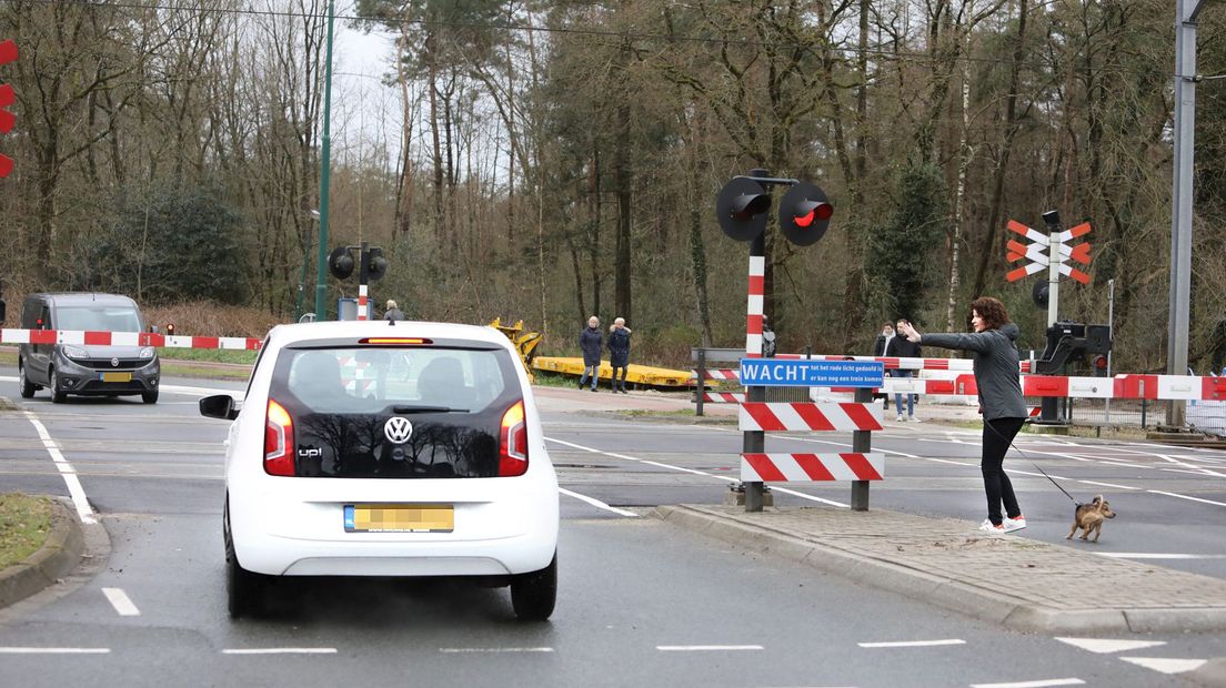 Een auto probeerde zaterdag in Baarn gesloten spoorbomen te omzeilen. Een voetganger waarschuwt voor een naderende trein.
