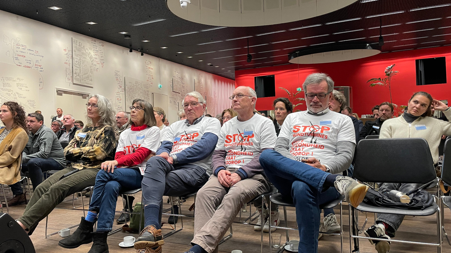 Tegenstanders van windmolens luisteren naar de insprekers
