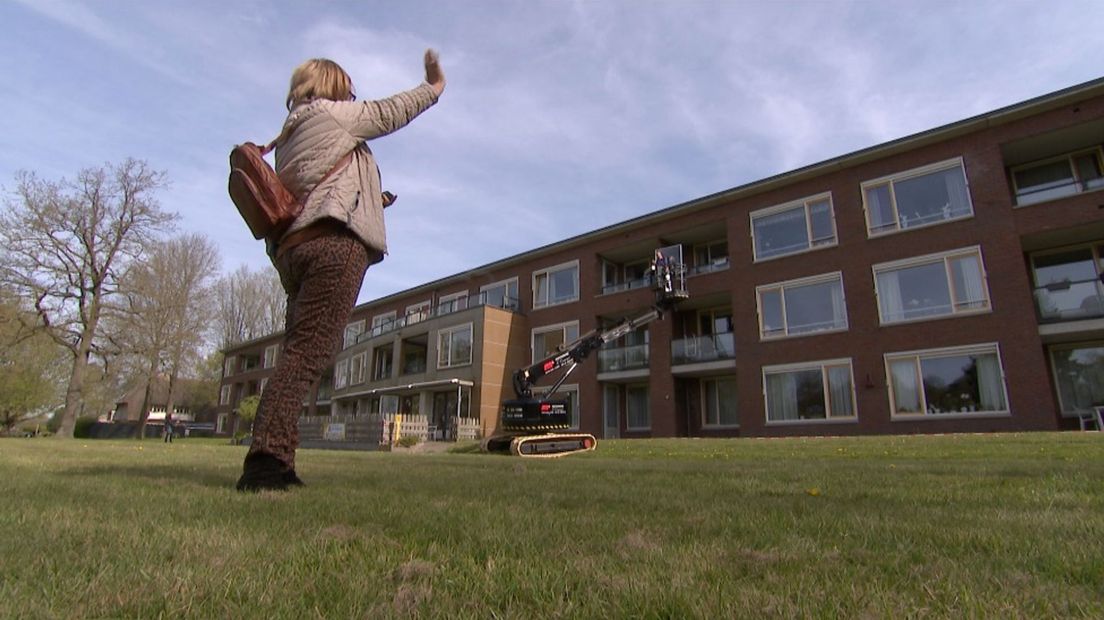 Dochter zwaait naar haar moeder achter het raam