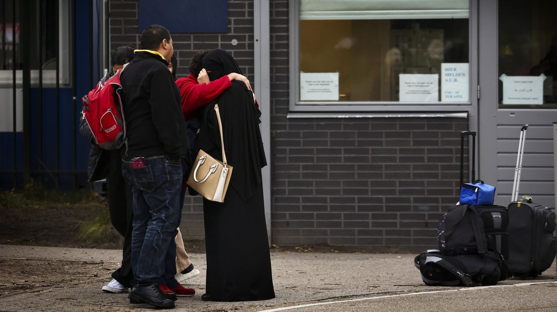 Asielzoekers wachten bij de poort van het aanmeldcentrum van de IND in Ter Apel