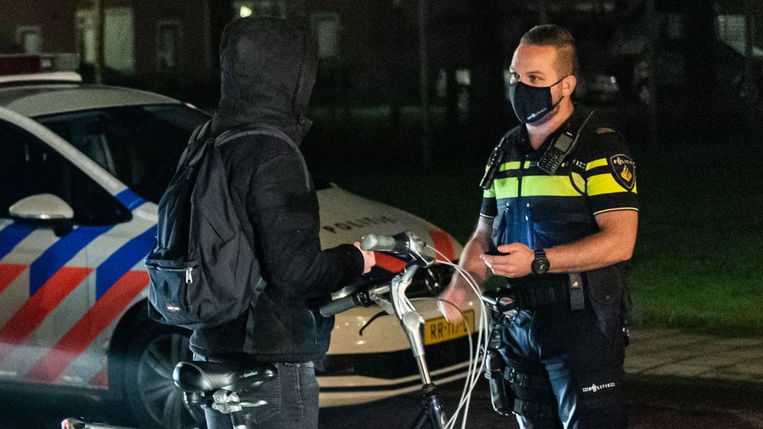 Agent met mondmasker voert handhaving coronaregels uit.