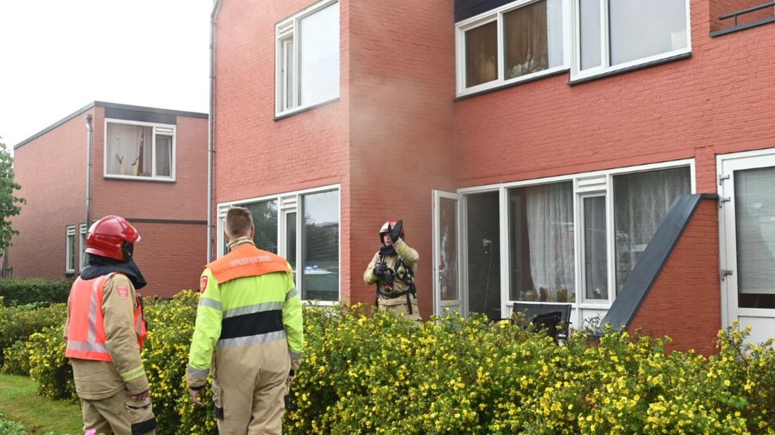 Brandweerlieden bij de woning in Appingedam, waarvan net de deur is geforceerd