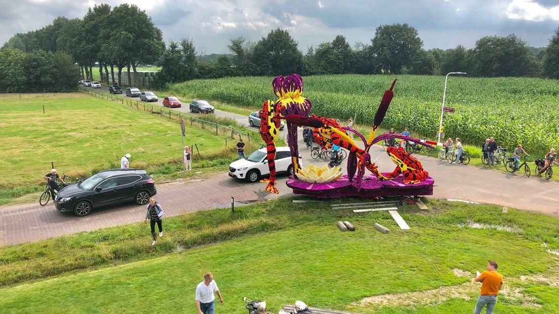 Auto's rijden af en aan langs de corsowagens.