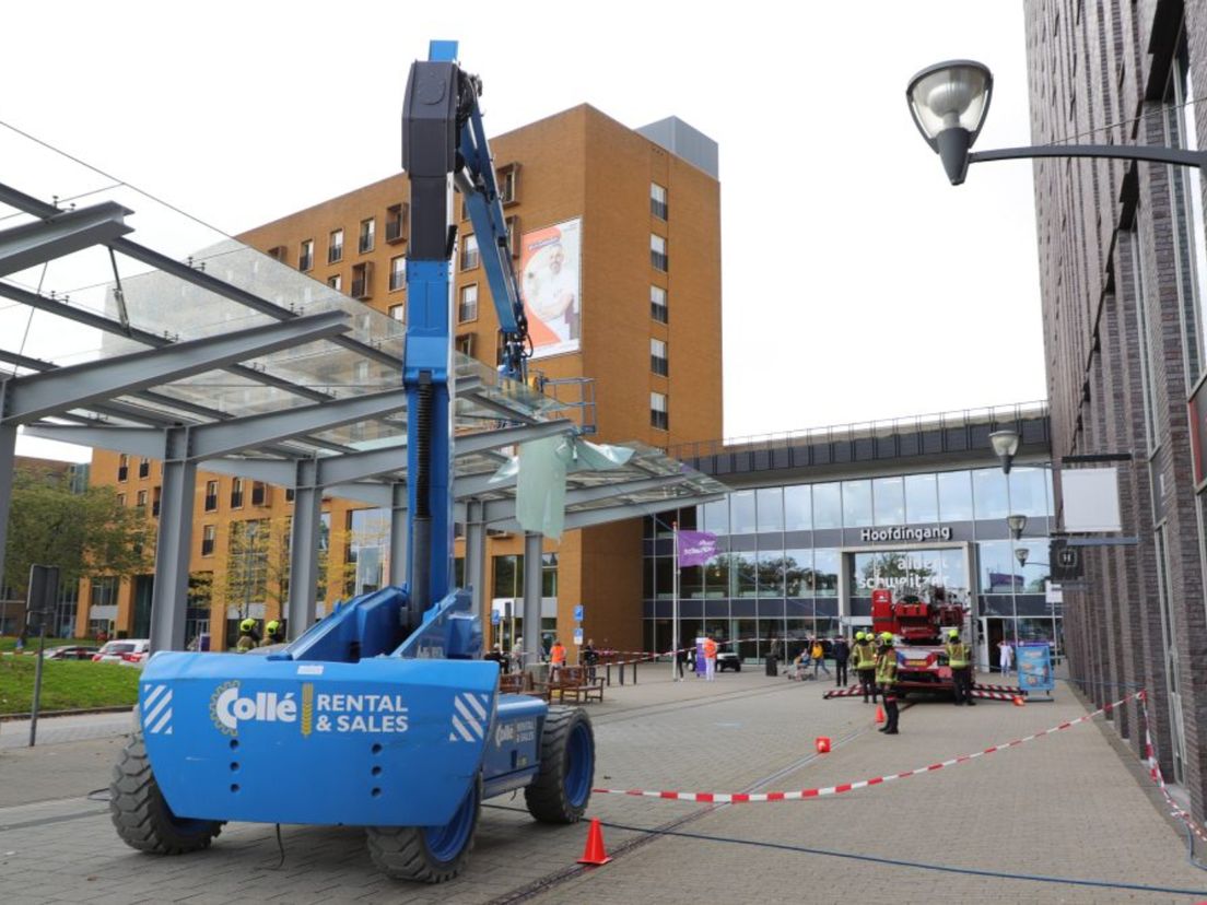 De hoogwerker viel na de klap tegen de glazen overkapping uit, waarna de medewerker vast kwam te zitten.