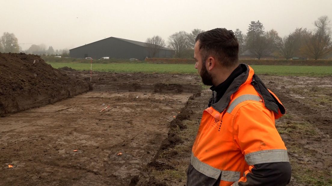 Archeoloog Stijn van As kijkt naar een kuil met sporen van vroege bewoning