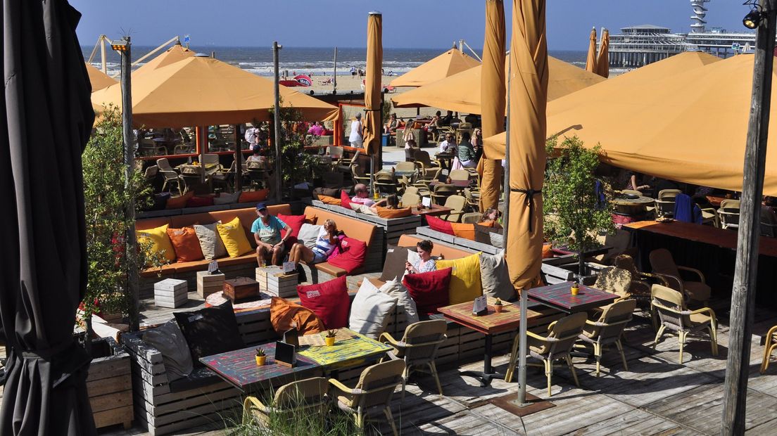 Strandgasten genieten van een drankje bij een strandtent op Scheveningen 