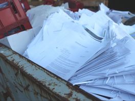 Brieven over verkeersboetes gedumpt in afvalcontainer, namen en adressen waaien over straat