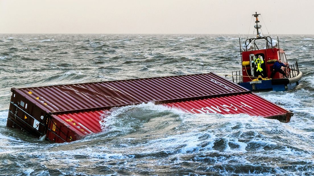 Een sleepboot brengt twee overboord geslagen containers van het schip MSC Zoe de haven binnen.