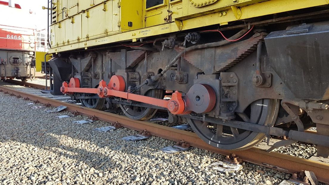 De ontspoorde locomotief staat net naast de rails op het rangeerterrein.