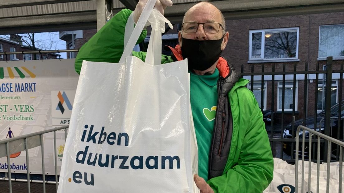 Ondernemers op de Haagse Markt delen voedselpakketten uit.