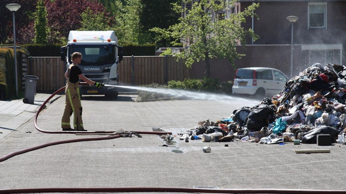 Brandweer blust afval op straat in Goor