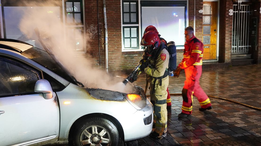 De brandweer blust het vuur in de auto