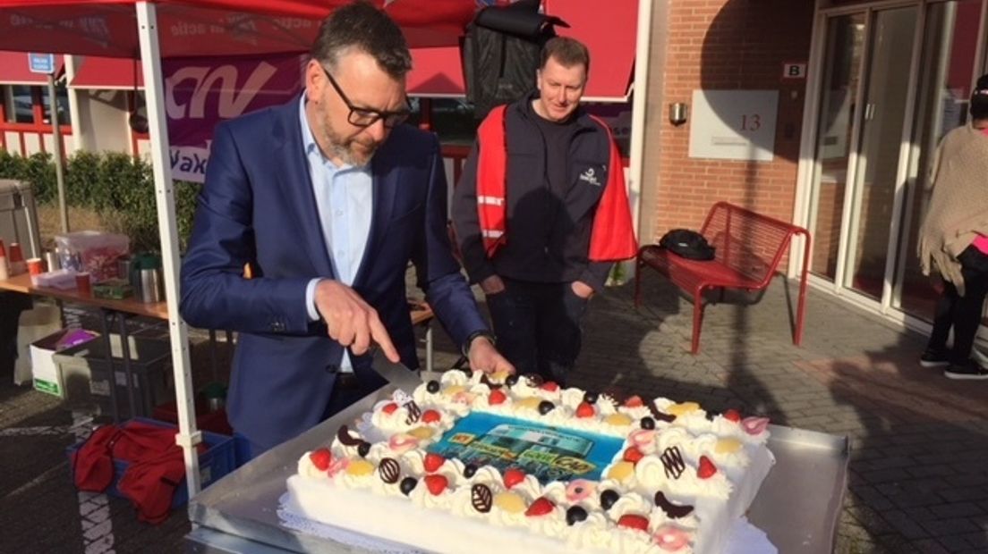 Directeur Robert de Ridder van woonservice l'escaut snijdt de in ontvangst genomen taart aan.