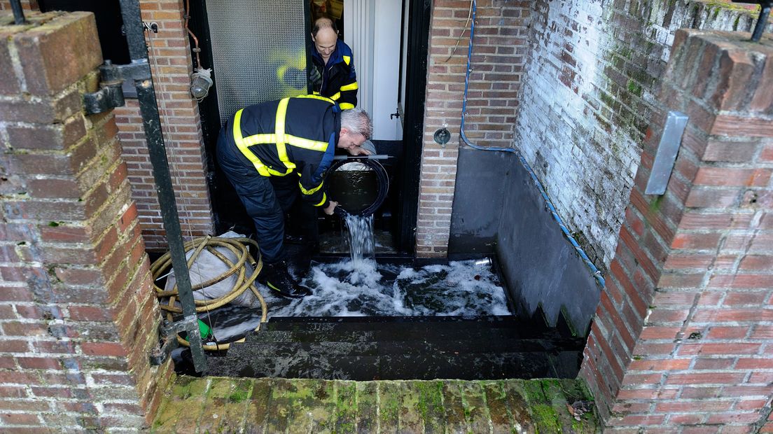 Brandweerlieden pompen een kelder leeg.