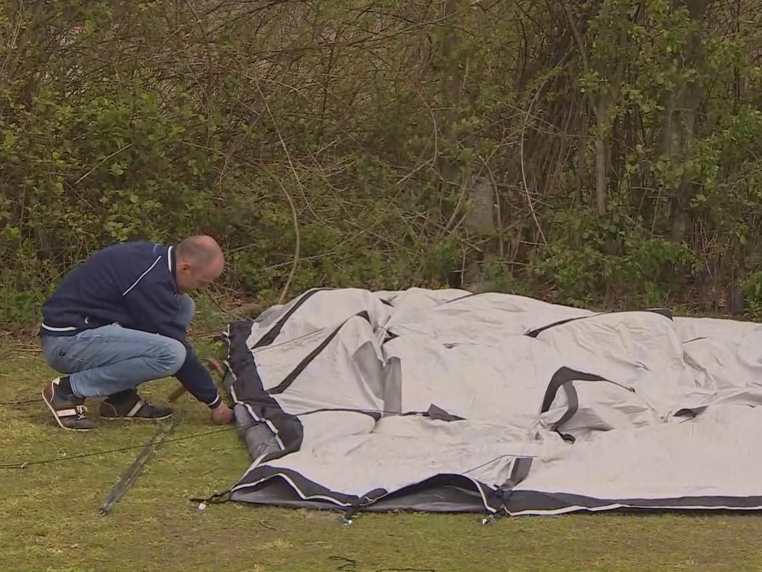 Een campinggast slaat zijn haringen terug in een omgewaaide tent