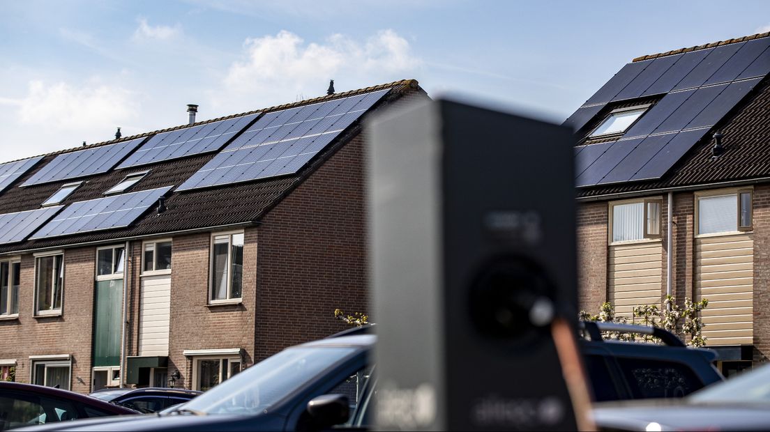 Een elektrische auto aan de laadpaal. in een wijk met zonnepanelen