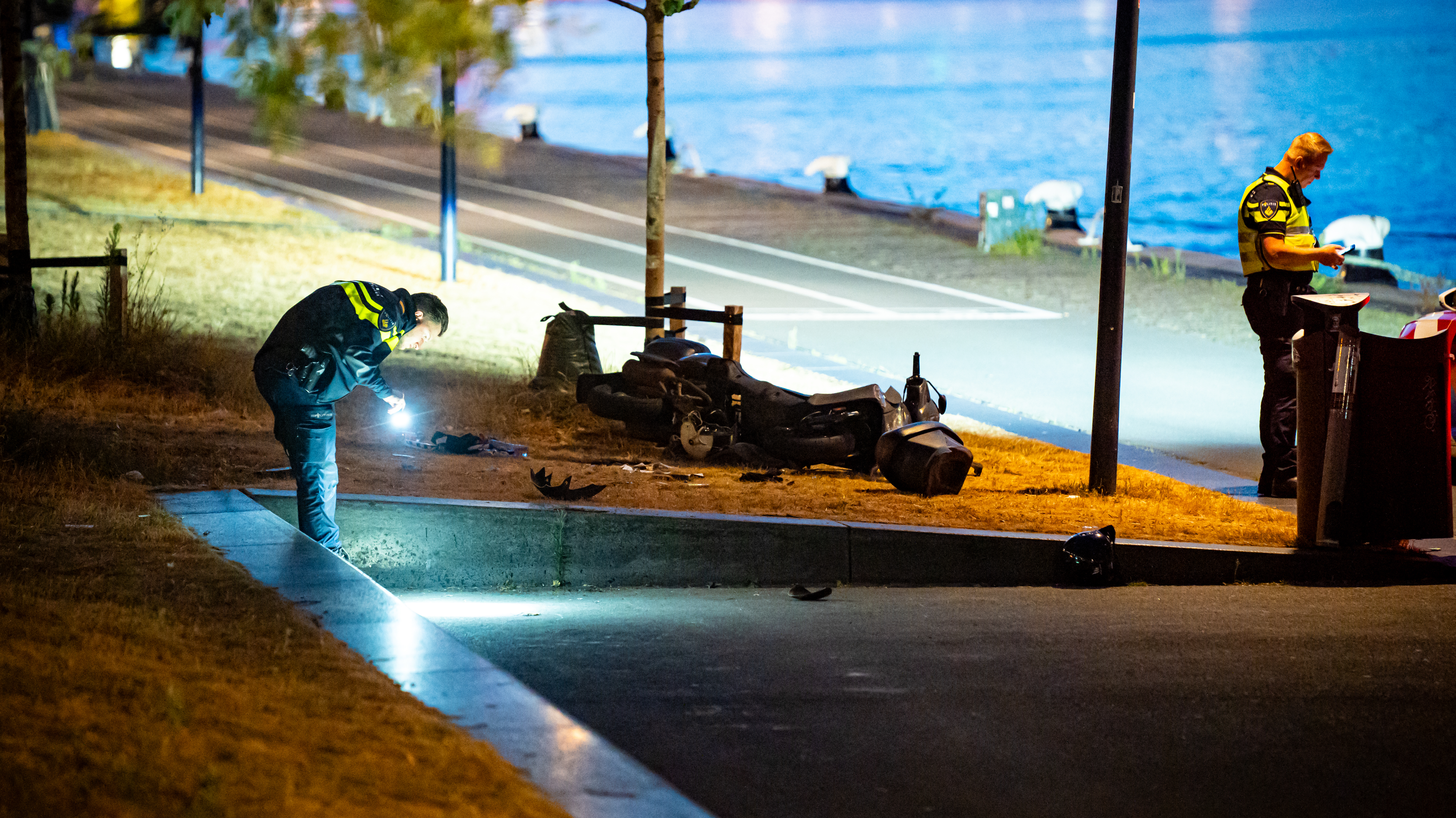De politie doet onderzoek in de buurt van de gecrashte scooter