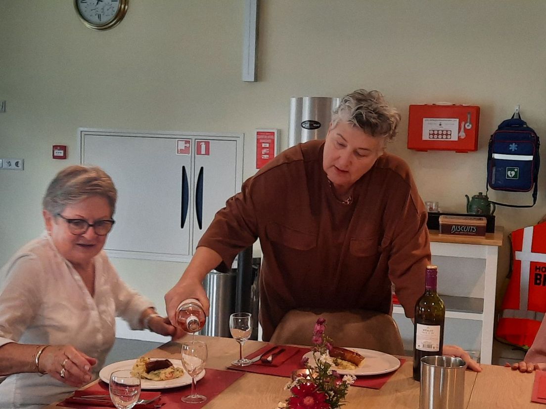 Gastvrouw Ellen Stok schenkt de wijn in voor een gast.