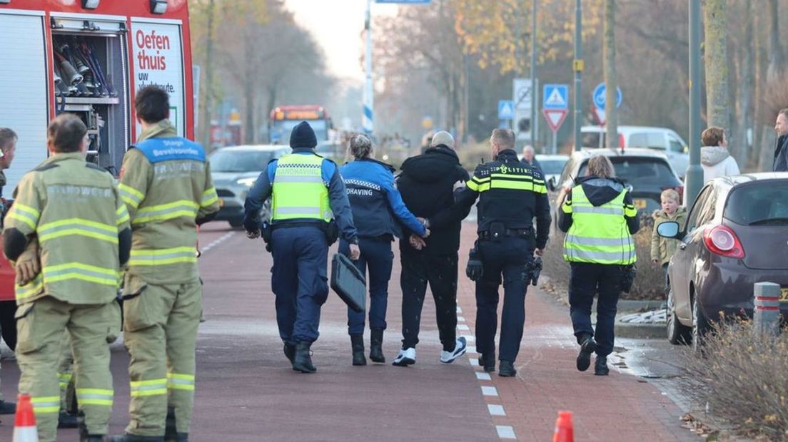 De politie neemt de aangehouden man mee.