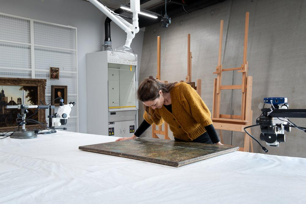 Restaurator Erika Smeenk-Metz bekijkt het schilderij.