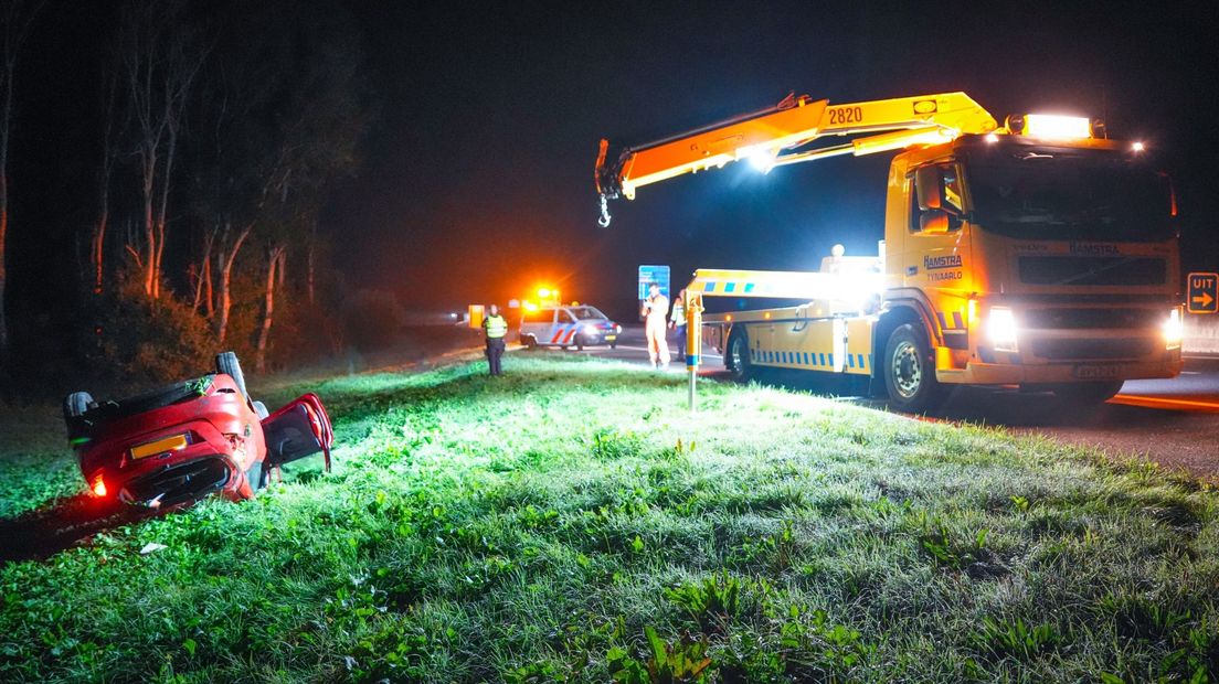 De auto ligt op de kop in de berm