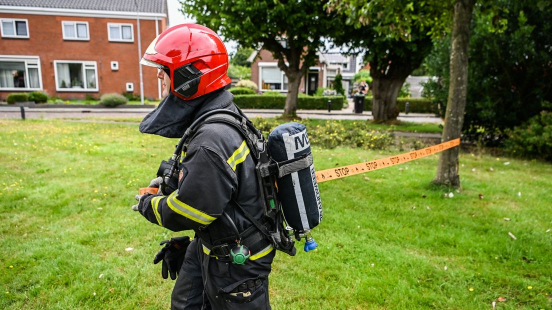 Een brandweerman zet het gebied rond de woning af