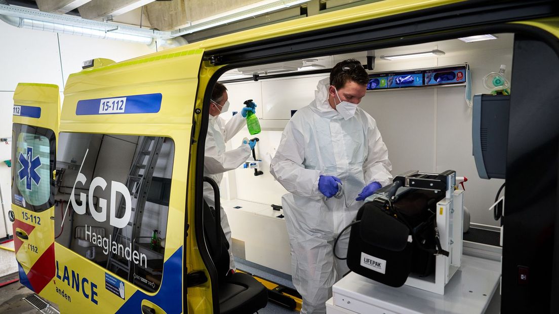 Ambulancepersoneel van GGD Haaglanden reinigt een ziekenauto nadat er hulp is verleend aan een patiënt.