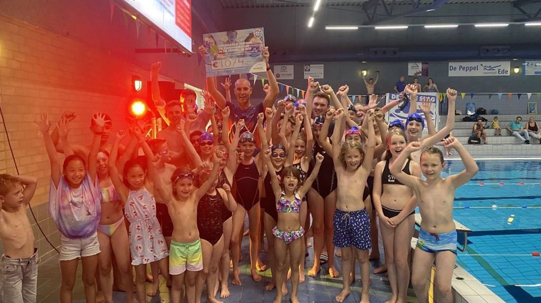 Maarten krijgt cheque met opgehaalde geld deelnemers Zwem4daagse