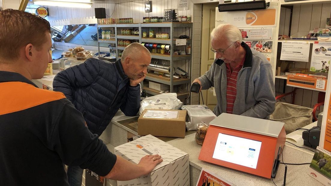 Gert (leunend op de balie) en Anne Nienhuis bezig met de post