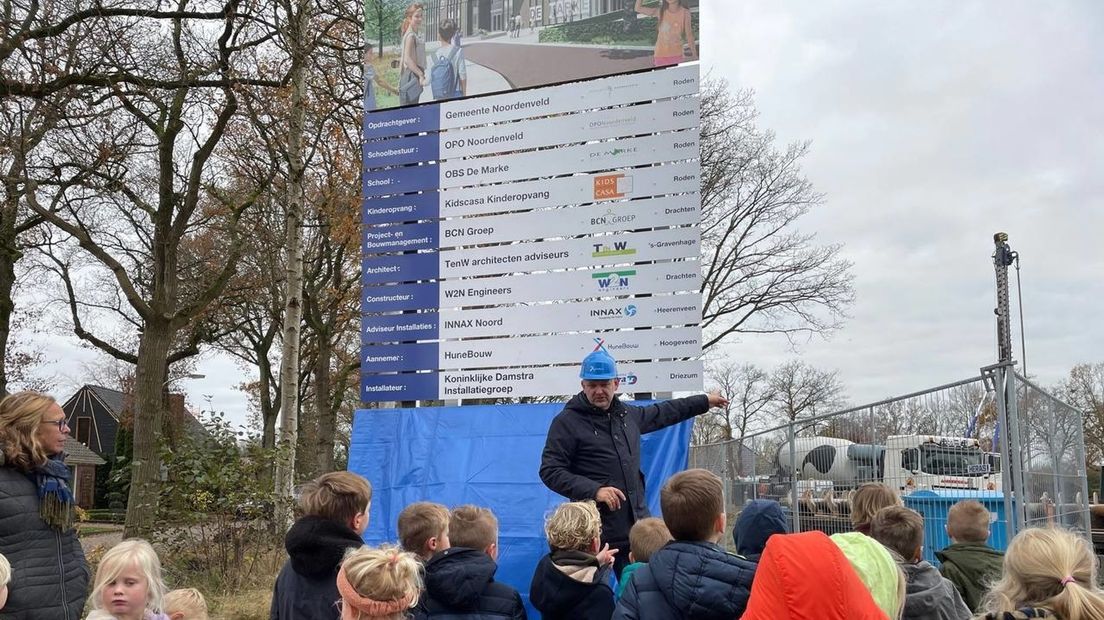 Wethouder Alex Wekema geeft uitleg aan leerlingen van De Marke bij het pas onthulde bouwbord.