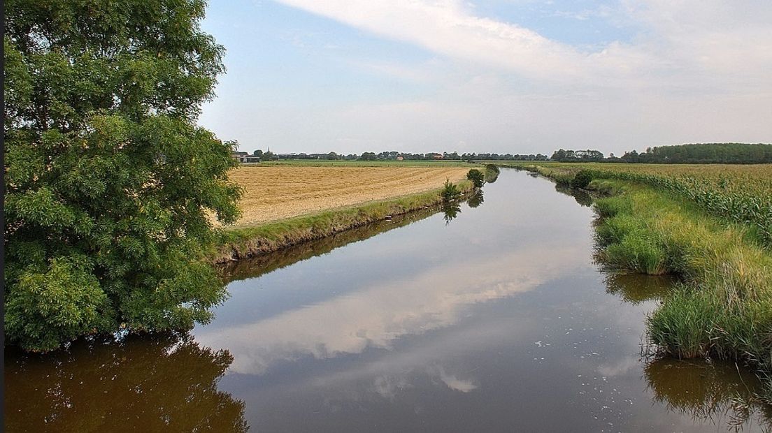 Weerspiegeling van overdrijvende wolken in het water van een watergang bij Ritthem.