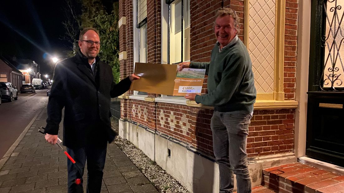 Wethouder Eltjo Dijkhuis (links) overhandigt de cheque aan Jan-Dirk Gardeniers van KunstKerk in Warffum