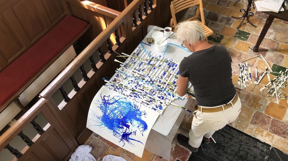 Kunstenaar Ina Fekken werkt in de kerk van Den Andel met draad en stukjes papier.