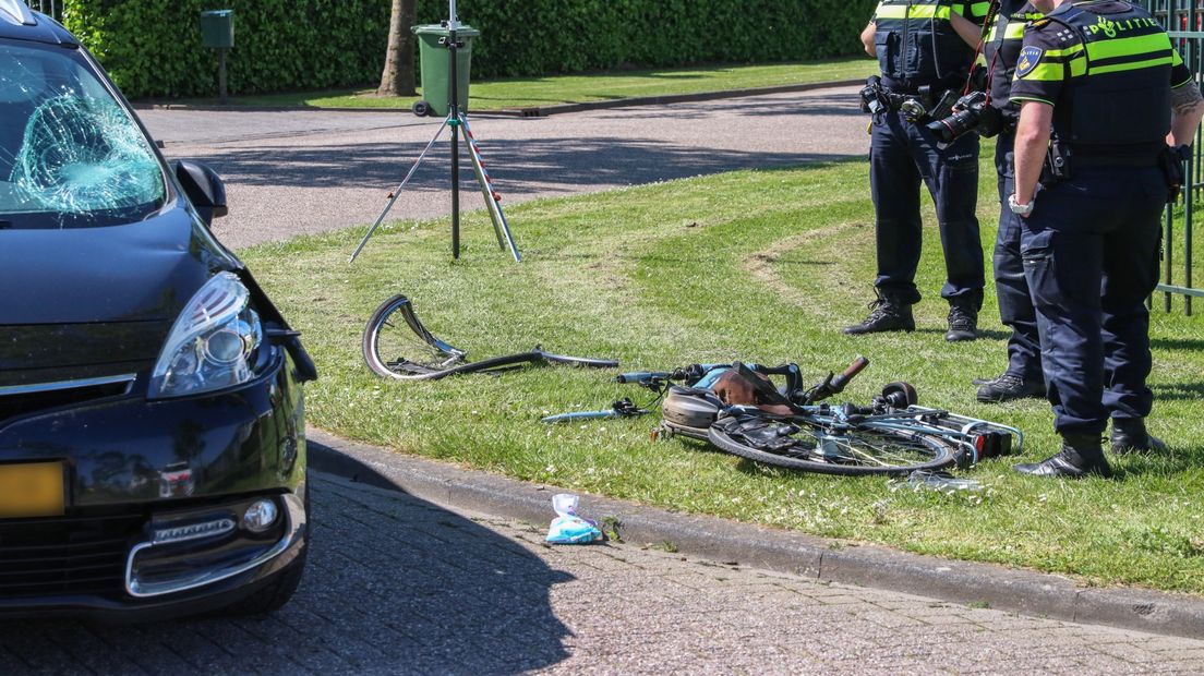 Agenten kijken naar een beschadigde e-bike nadat de bestuurder in botsing kwam met een automobilist