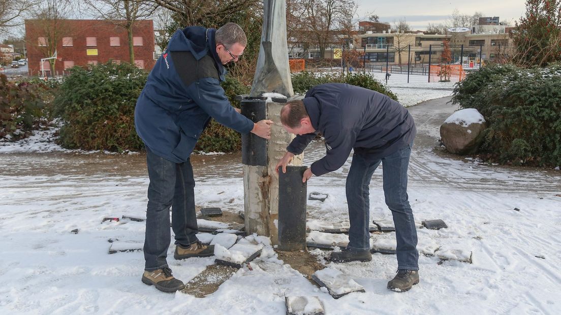 Medewerkers van de gemeente bekijken de schade aan het kunstwerk in de wijk het Zwering