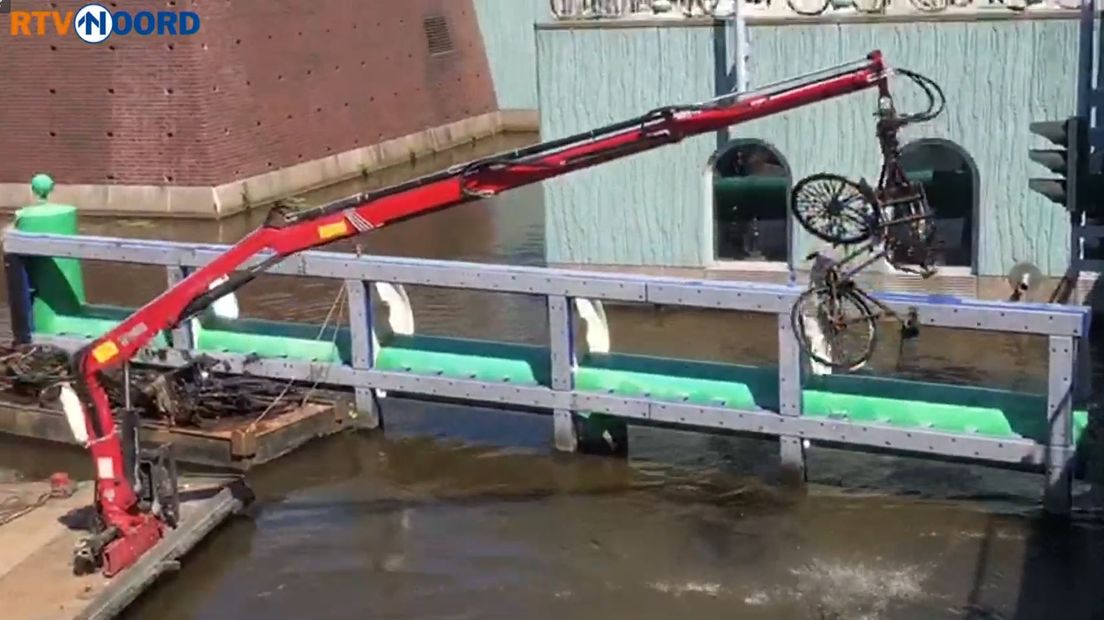 Een fiets wordt uit het water bij het Groninger Museum gehaald.