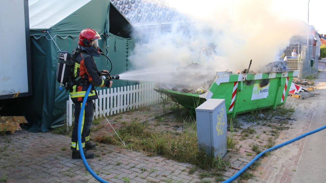 De brandweer blust de container in Heiligerlee