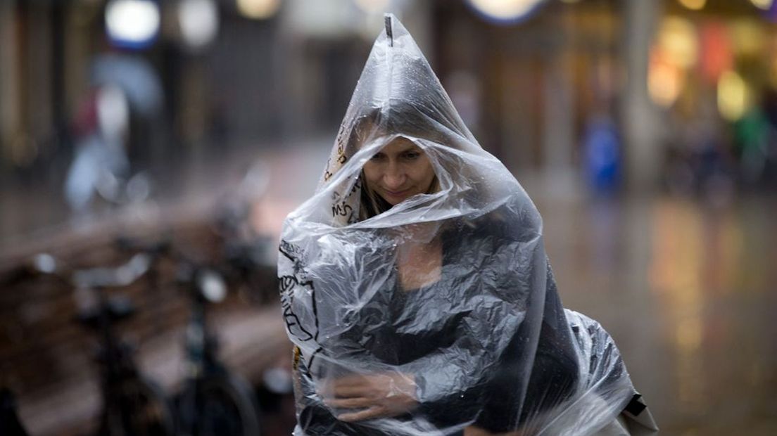 Een vrouw met poncho trotseert de regen.