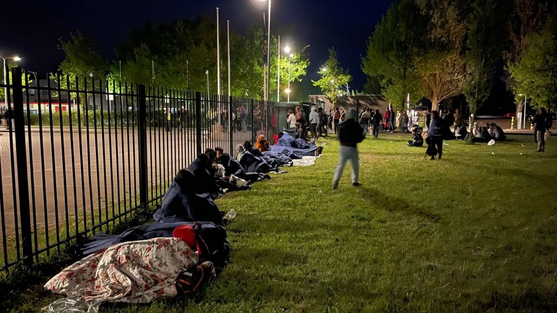 De asielzoekers moeten urenlang buiten de hekken wachten op een oplossing