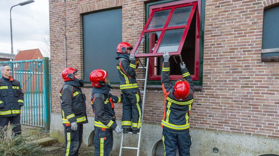 De brandweer slaat een ruit kapot van het KPN-gebouw in Appingedam.
