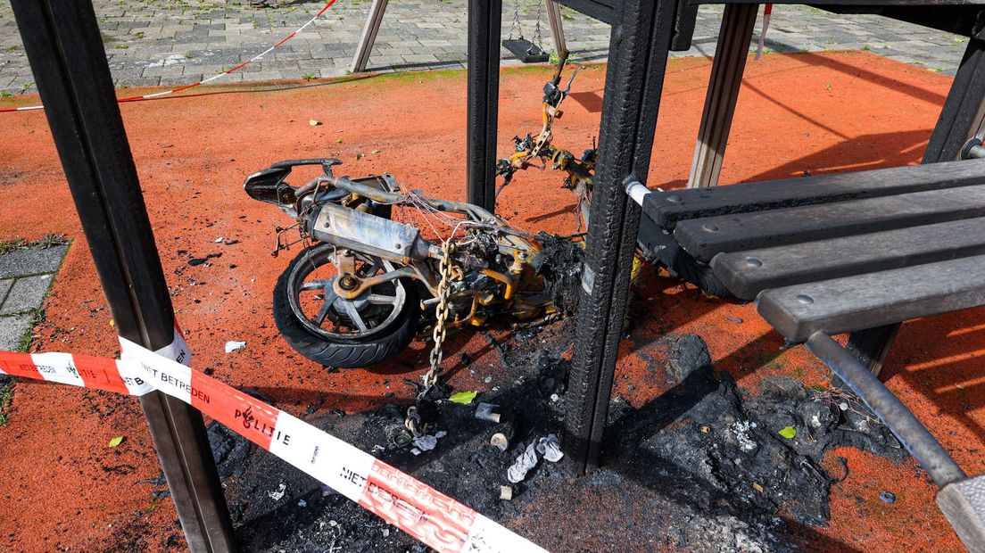 De scooter ligt uitgebrand onder een van de speeltoestellen.