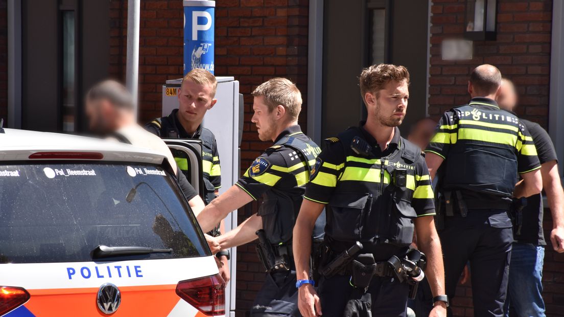 Een van de aangehouden mannen gaat mee met de politie.