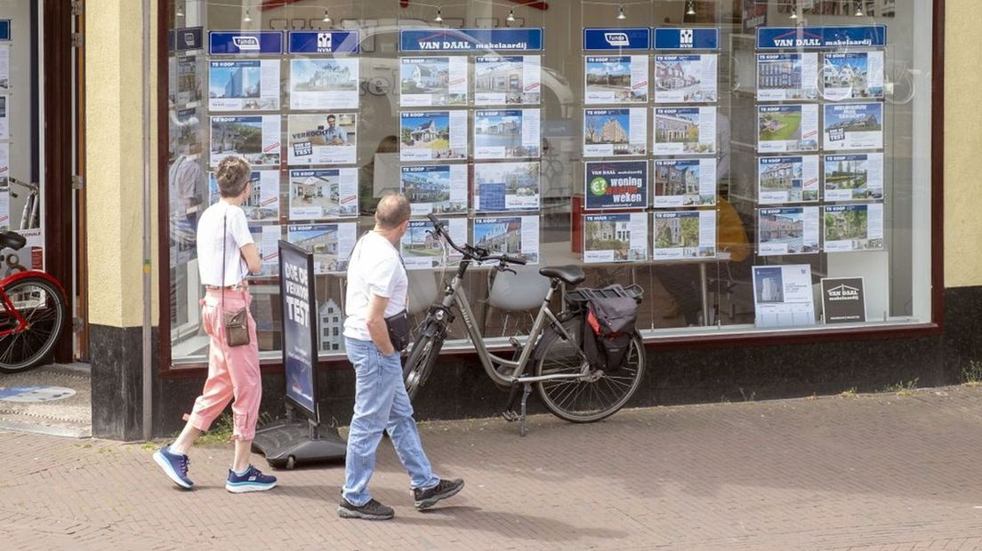 Woningzoekenden of geïnteresseerden staan te kijken welke woningen nog te koop staan bij een makelaar