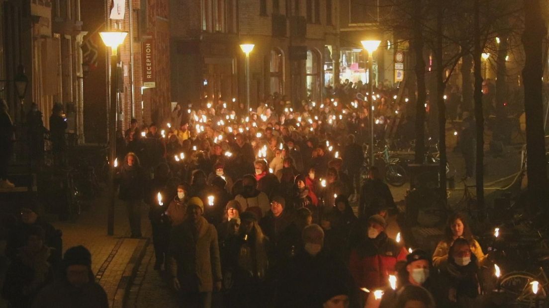 Een lange stoet met mensen en fakkels