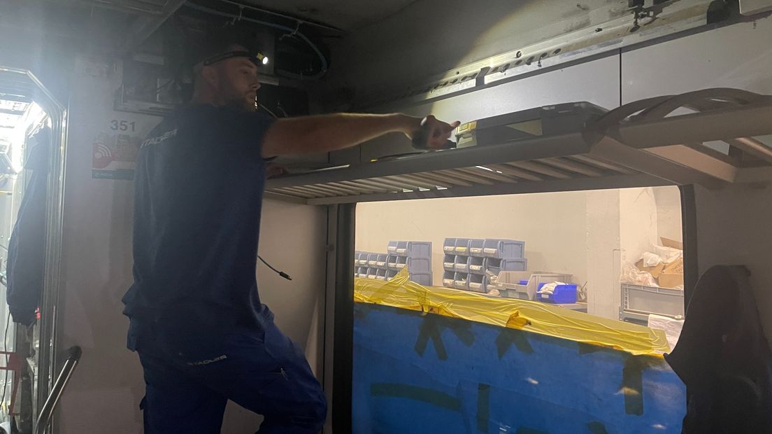 Eén van de werknemers van Stadler werkt met een lampje op aan de trein