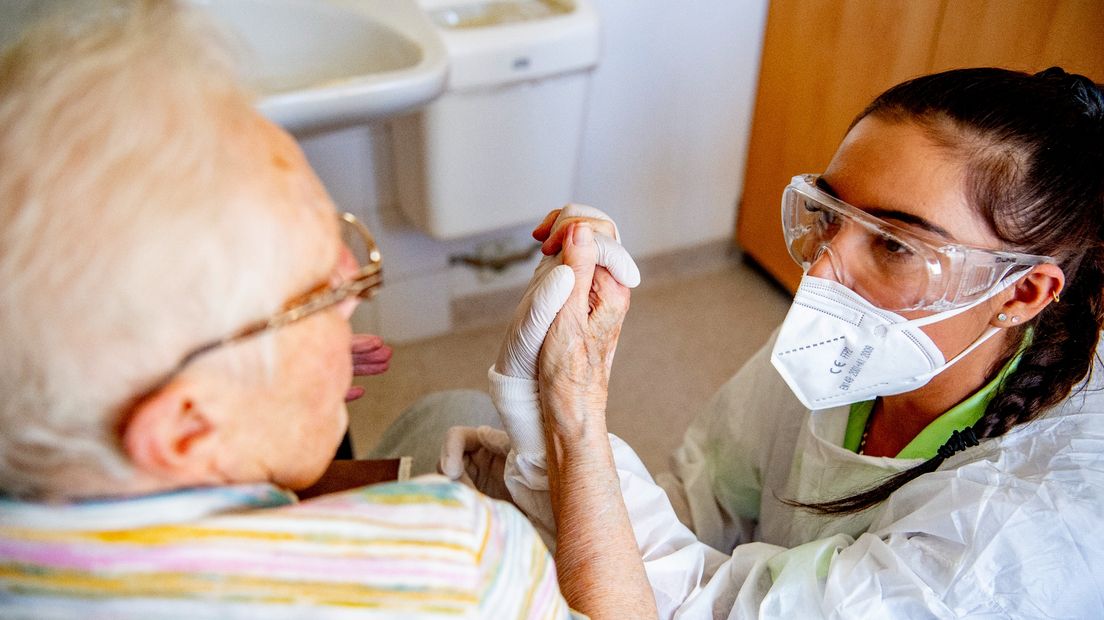 Een zorgmedewerker helpt een bewoner van een verpleeghuis