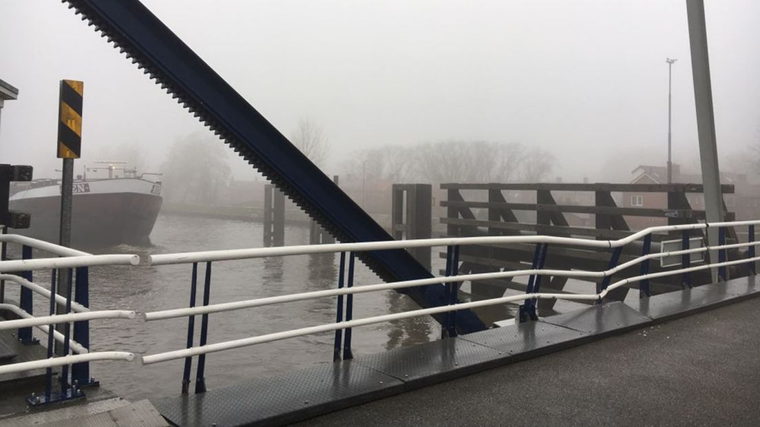 Het schip voer in de mist tegen de dichte brug