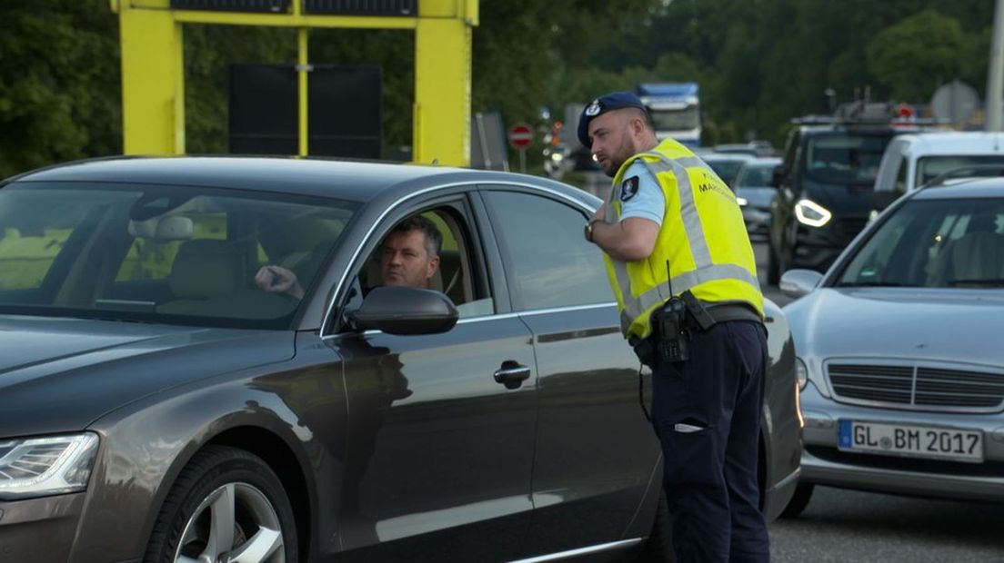 Een marechaussee spreekt met een bestuurder tijdens een controle.