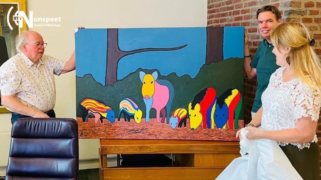 Kunstenaar Leen Bosman overhandigt het schilderij aan wethouder Elskamp.